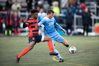 UNC's Jeremy Kelly prepares to kick the ball as Syracuse's Mo Adams applies pressure.