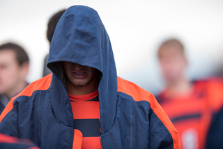 A Syracuse player walks off the field with his hood over his head.